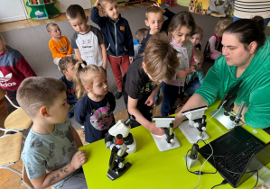 Prowadząca objaśnia jak działa mikroskop, dzieci słuchają