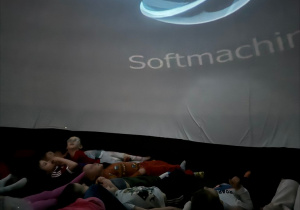 Dzieci na leżąco oglądają film edukacyjny w kinie sferycznym
