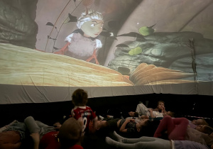 Dzieci na leżąco oglądają film edukacyjny w kinie sferycznym