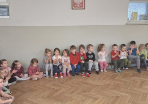 Dzieci siedzą i słuchają o pokazywanych przez muzyka instrumentach.