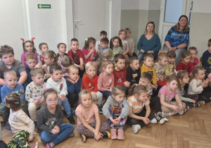 Dzieci siedzą i słuchają o pokazywanych przez muzyka instrumentach