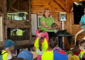 Pracownik ZOO opowiada dzieciom o żółwiu, dzieci siedzą i słuchają