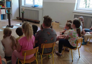 Dzieci z grupy IV siedzą na krzesełkach i słuchają informacji o sowach