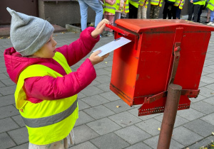 Dziecko wrzuca swój list do skrzynki pocztowej