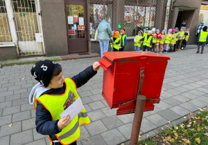 Dziecko wrzuca swój list do skrzynki pocztowej