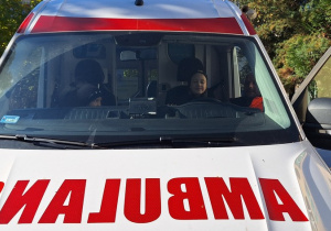 Dzieci oglądają ambulans, włączają sygnały dźwiękowe i świetlne