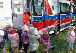 Dzieci stoją przy karetce i kolejno wchodzą obejrzeć auto od środka