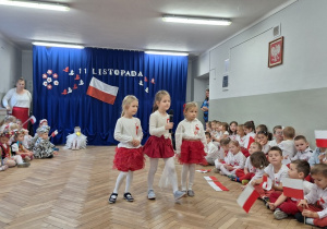 Dziewczynki mówią do mikrofonu swoje części wspólnego wiersza patriotycznego