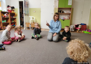 Nauczycielka opowiada dzieciom dlaczego czosnek jest tak niezwykły, dzieci siedzą w kole na dywanie