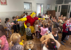 Dzieci tańczą ze swoimi przytulankami, Miś Puchatek tańczy między dziećmi