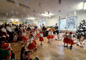 Na scenie dzieci tańczą do piosenki, w tle stoją rodzice na widowni