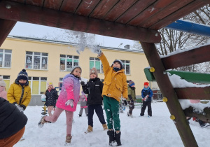 Dzieci rzucają kulkami ze śniegu do celu