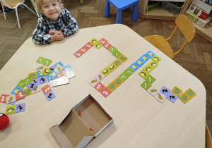 Przy stoliczku dziewczynka układa domino ze zwierzątkami