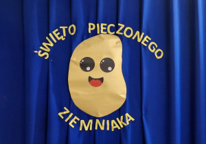 Dekoracja - na granatowym materiale napis święto pieczonego ziemniaka i wycięty ze złotego papiery ziemniak