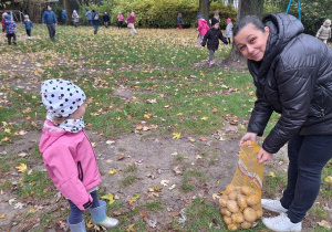Nauczycielka z grupy III trzyma worek do którego dzieci z jej grupy wrzucają znalezione ziemniaki