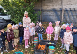 Zdjęcie grupowe dzieci przy pojemniku z marchewkami przygotowanymi dla alpak.