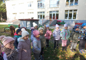 Dzieci stoją i słuchają informacji o alpakach