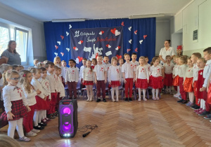 Dzieci na stojąco śpiewają piosenkę o Polsce