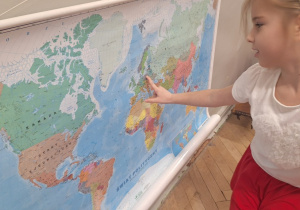 Dziewczynka pokazuje gdzie na mapie świata znajduje się Polska