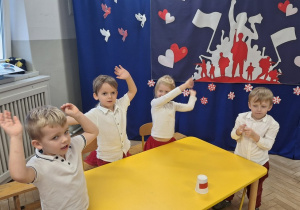 Dzieci na stojąco śpiewaja fragment piosenki jako "okrzyk radości po zdobytym punkcie dla grupy"