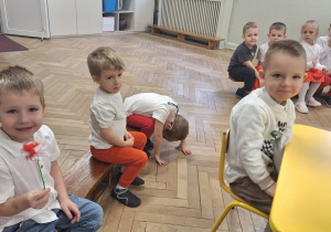 Chłopiec pokazuje kwiatek z bibuły, który otrzymał w nagrodę za dobrą odpowiedź