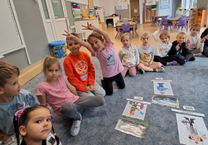 Dzieci siedzą w kole i utrwalają numery telefonów alarmowych