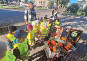 Dzieci stoją i oglądają dynie przed sklepem