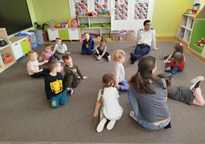 Dzieci siedzą na dywanie i słuchają opowiadań o samolotach, lotnisku i pracy pilota