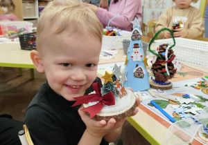 Chłopczyk prezentuje wykonane przez siebie ozdoby świąteczne