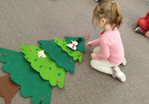 Dziewczynka przyczepia bałwanka na choinkę