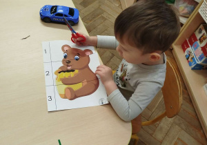 Chłopczyk wycina nożyczkami po linii Misia