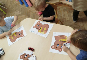 Chłopcy próbują wyciąć po linii nożyczkami