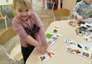 Dziewczynka dopasowuje obrazki łącząc je w całość