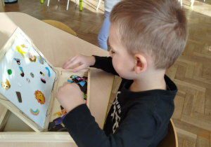 Chłopczyk układa obrazek na tablicy magnetycznej