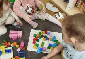 Dzieci układają ślimaczka na kartce z klocków