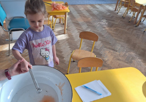 Dziecko trzyma klucz, nauczycielka leje wosk przez dziurkę