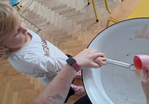 Dziecko trzyma klucz, nauczycielka leje wosk przez dziurkę