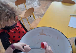 Dziecko trzyma klucz, nauczycielka leje wosk przez dziurkę