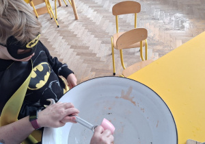 Dziecko trzyma klucz, nauczycielka leje wosk przez dziurkę