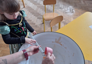 Dziecko trzyma klucz, nauczycielka leje wosk przez dziurkę