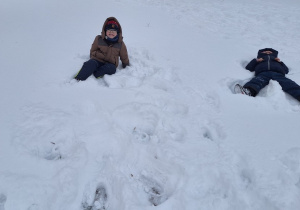 Dzieci robią aniołki na śniegu