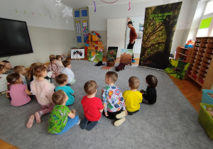 Dzieci słuchają informacji o mrówkach i oglądają pokazywane zdjęcia dotyczące mrówek