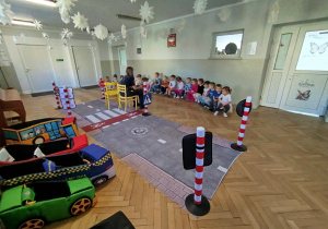 Dzieci siedzą na ławeczce i rozmawiają o bezpieczeństwie w ruchu pieszych