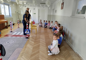 Dzieci siedzą na ławeczce i rozmawiają o bezpieczeństwie w ruchu pieszych