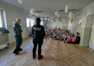 Pani Policjantki witają się z dziećmi i rozmawiają z przedszkolakami na temat bezpieczeństwa podczas drogi do przedszkola