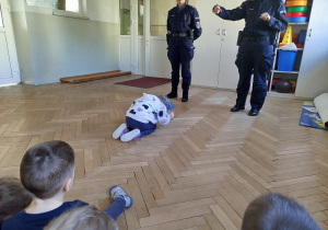 Policjantka wyjaśnia dzieciom dlaczego znajomość takiej postawy jest ważna dla dzieci
