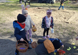 Dzieci zbierają jajeczka do swoich koszyczków