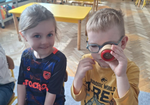 Dzieci patrzą przez szkiełka, które zmieniają obraz na taki jak widzą mrówki