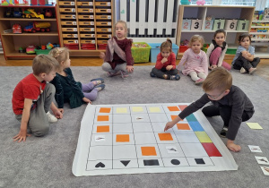 Dzieci układają karmnik na macie do kodowania wg kodu z tablicy