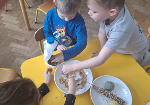Dzieci przygotowują mieszanki ziaren dla ptaków i wsypują do karmnika